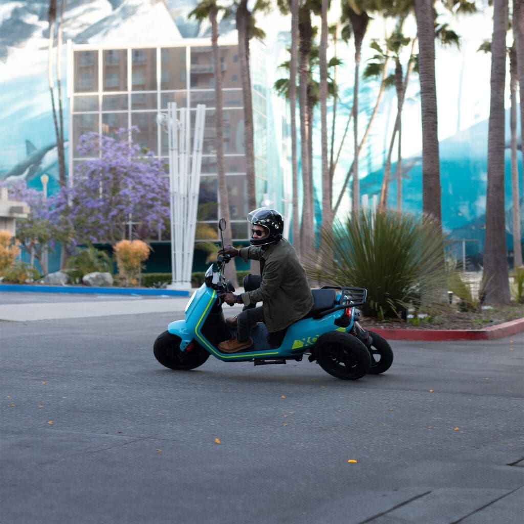 Side view of rider on XOTO 3-wheeled leaning electric scooter