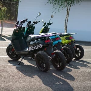 3 XOTO 3-wheeled electric scooters in black, blue, and green